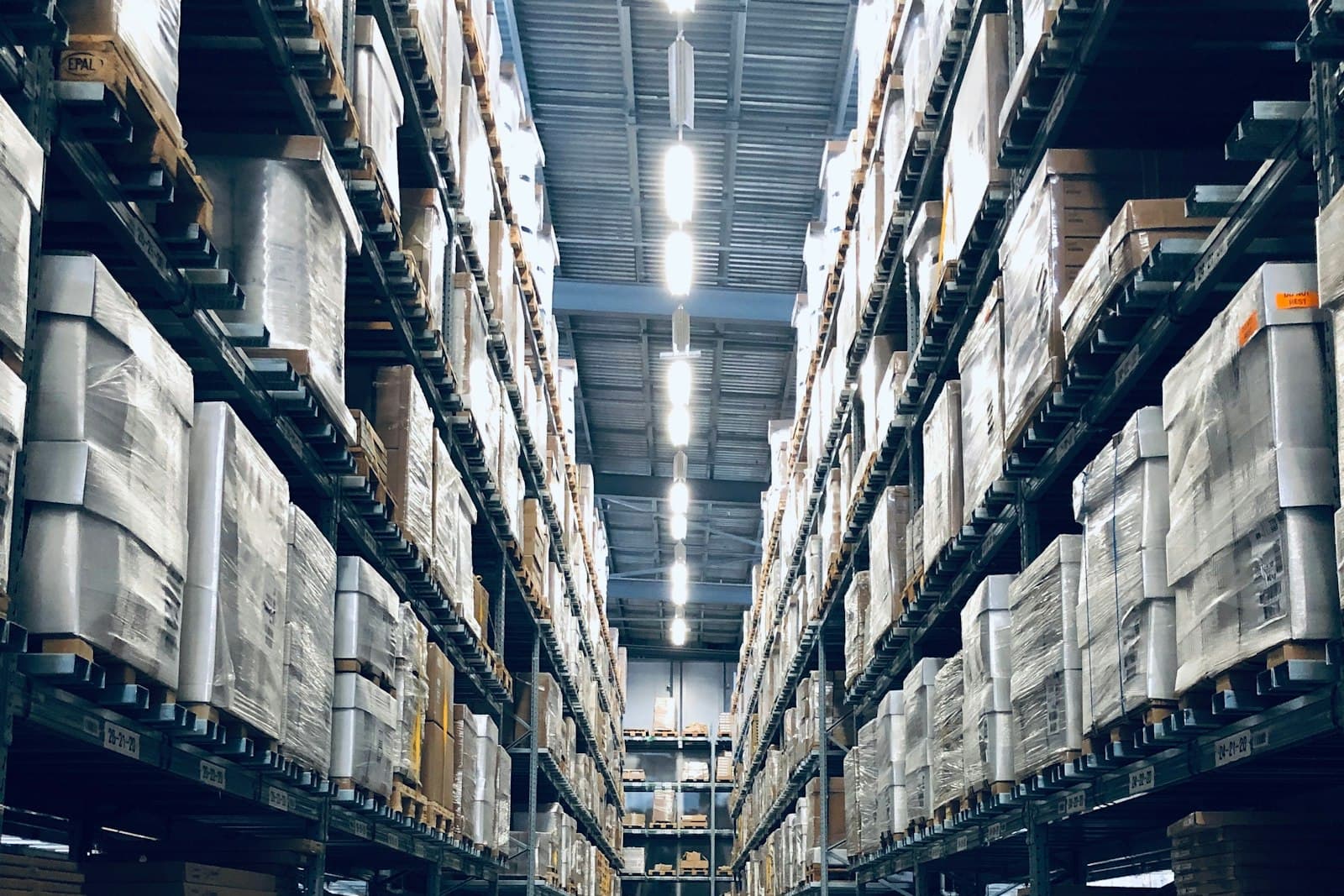 Pasillo de almacén con estanterías metálicas de varios niveles cargadas de producto